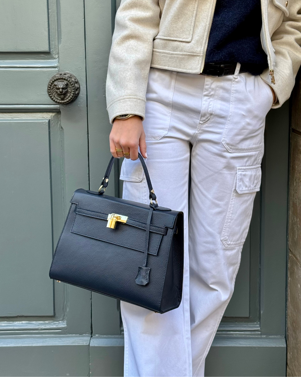 Detalle del cierre del bolso ICONIC 1984 BLUE, un bolso estilo Birkin con acabado en cuero italiano azul y herrajes dorados. La hebilla metálica, inspirada en los clásicos diseños de alta costura, añade un toque de lujo y exclusividad. Cada pieza ha sido cuidadosamente diseñada para brindar elegancia y seguridad al mismo tiempo.