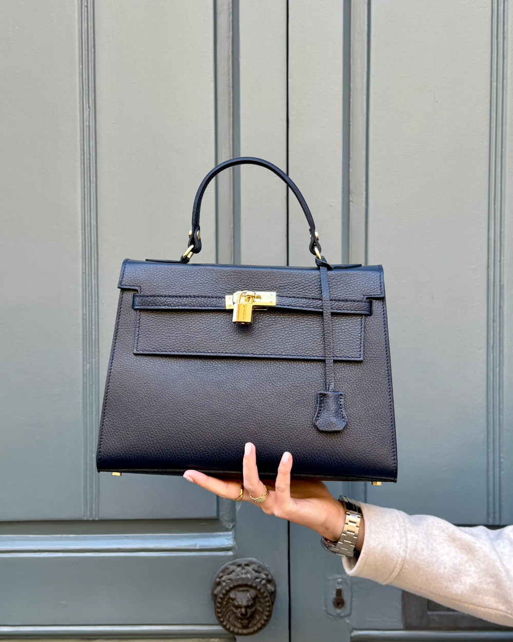 Detalle del cierre del bolso ICONIC 1984 BLUE, un bolso estilo Birkin con acabado en cuero italiano azul y herrajes dorados. La hebilla metálica, inspirada en los clásicos diseños de alta costura, añade un toque de lujo y exclusividad. Cada pieza ha sido cuidadosamente diseñada para brindar elegancia y seguridad al mismo tiempo.