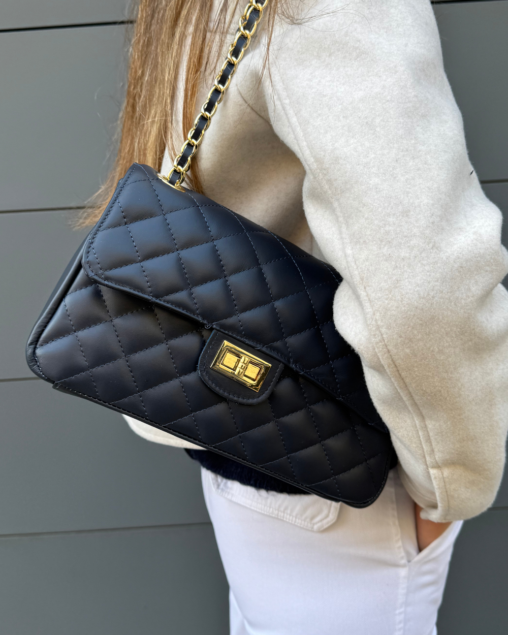 Vista lateral del bolso Juliette Navy, mostrando su estructura compacta y la cadena dorada combinada con cuero azul navy.