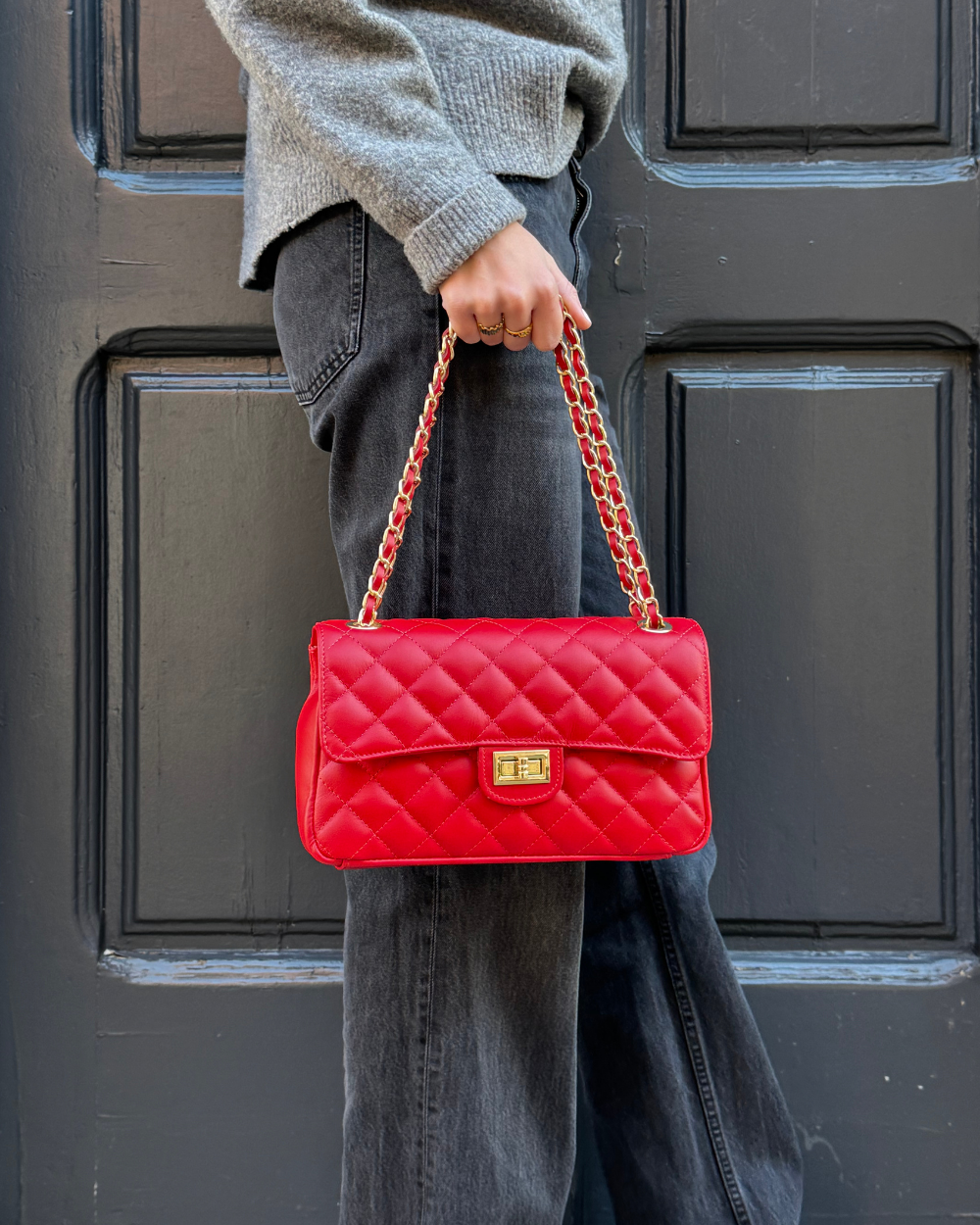 Vista lateral del bolso Juliette Red, destacando su estructura compacta y la combinación de cadena dorada con cuero vegano rojo.